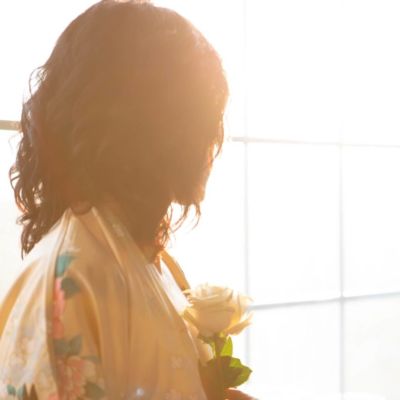 Femme devant une fenêtre s'offre une rose symbole de l'amour de soi