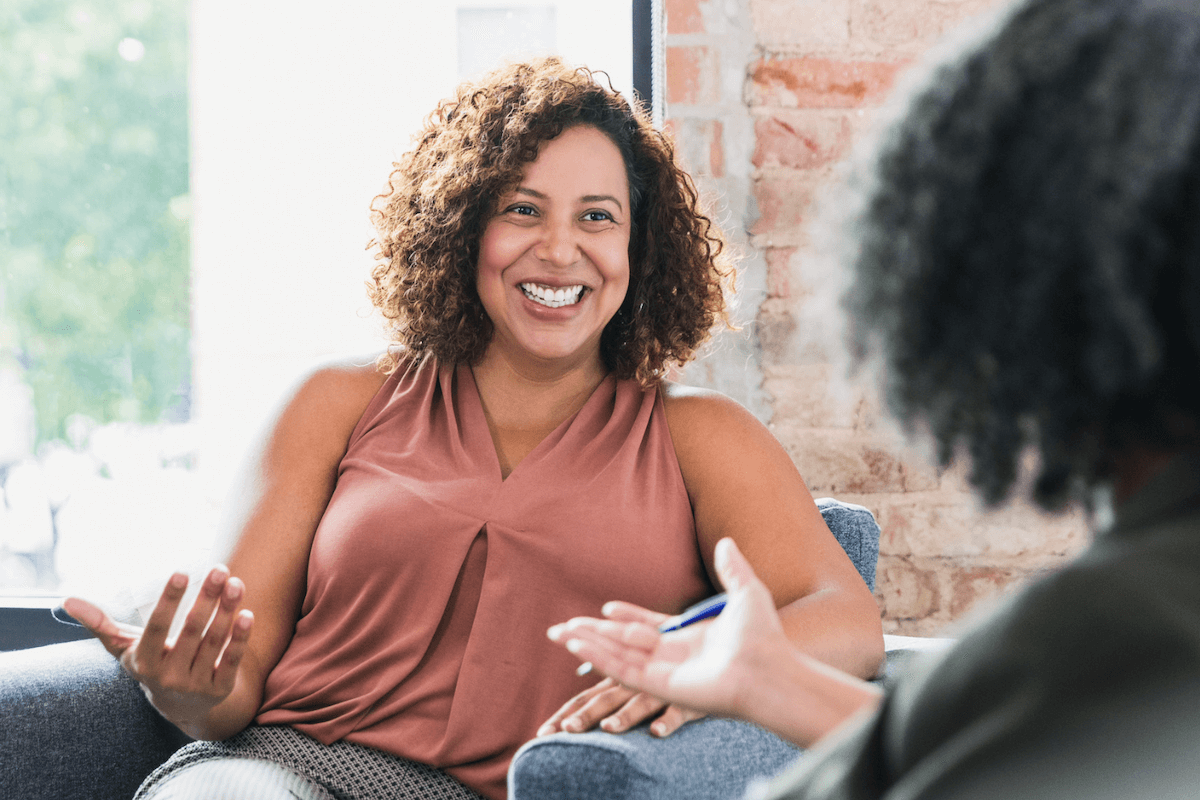 femme qui sourit dans un fauteuil en plein coaching s'affirmer